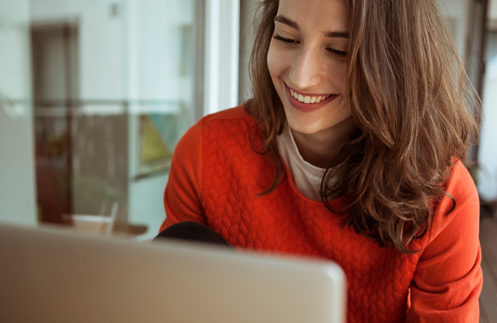 person smiling and looking at laptop