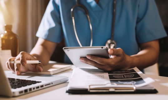 doctor sitting at desk holding a tablet