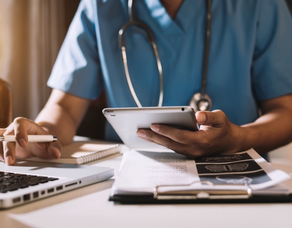 doctor sitting at desk holding a tablet