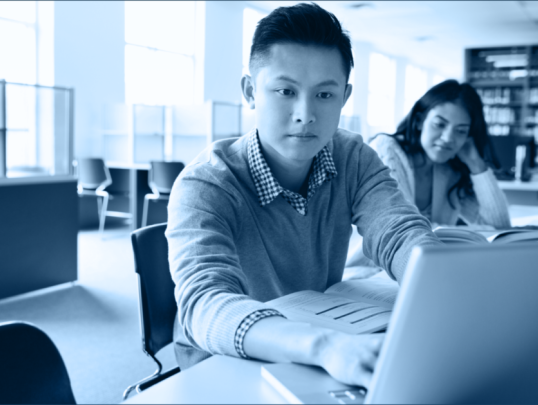 student sitting as desk working on laptop