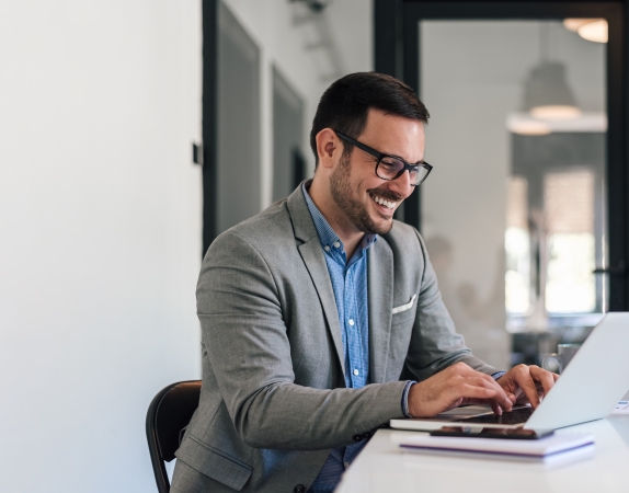 man smiling and typing on laptop