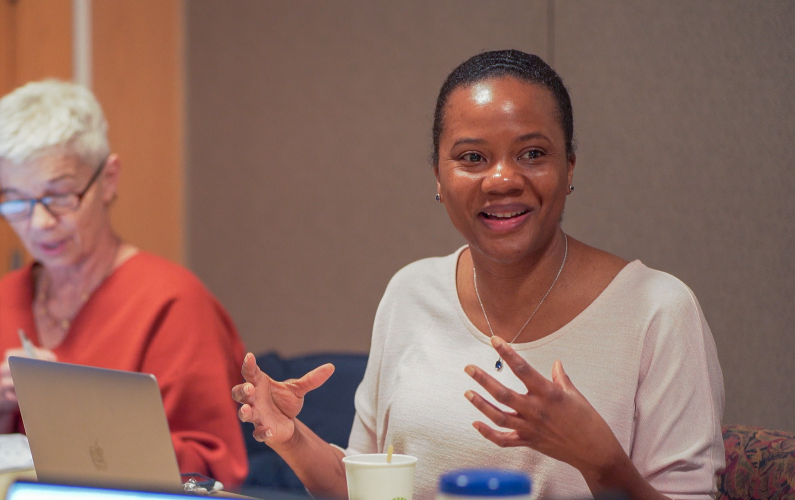 woman sitting at table speaking to group